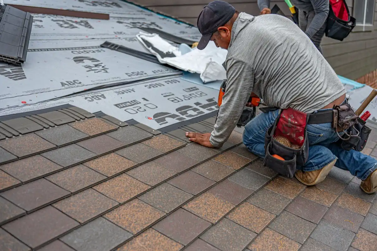 Roofing installer fastening shingles over new underlayment in Jackson, MS